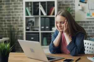 Exhausted woman resting at her desk, showing common burnout symptoms at work