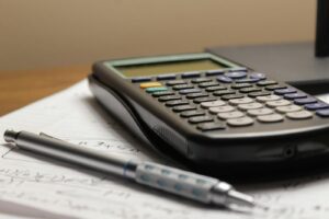 Notebook, calculator and laptop on a desk while working out how to price coaching sessions in South Africa