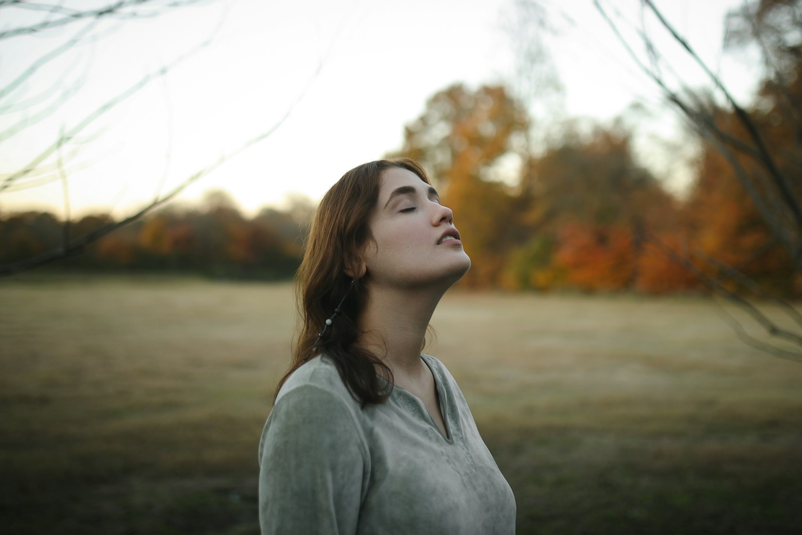 A woman sitting outdoors with her eyes closed, breathing slowly as a daily nervous system regulation practice